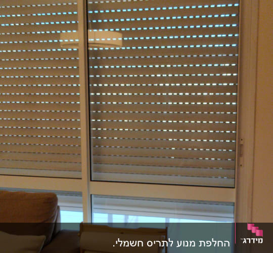תריסים סגורים עם חריצים לאור על חלון זכוכית